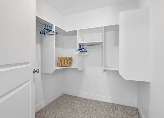 A white closet with a basket and hangers.