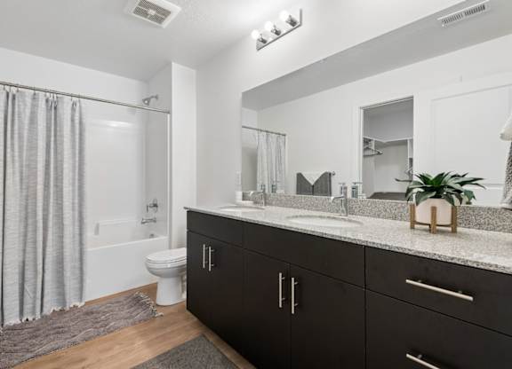 A bathroom with a sink, mirror, and bathtub.