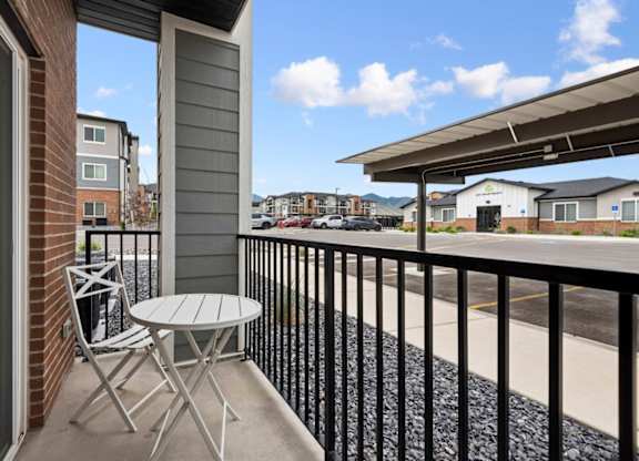 A balcony with a table and chairs overlooking a parking lot.