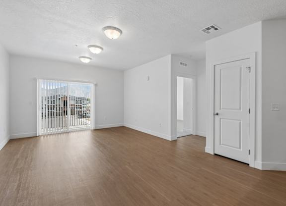 A room with a white door and a window with a view of a balcony.