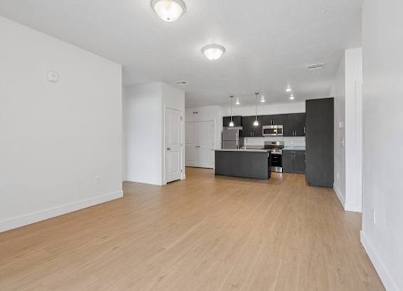 A spacious kitchen with wooden floors and white walls.