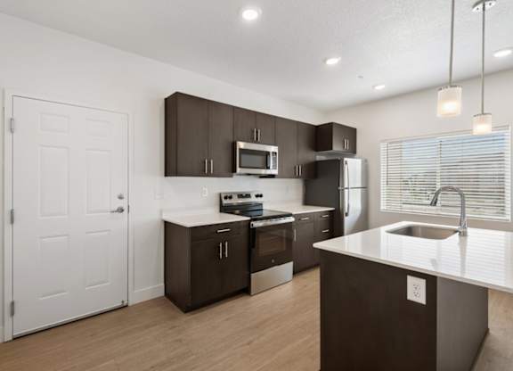 A modern kitchen with dark brown cabinets and stainless steel appliances.