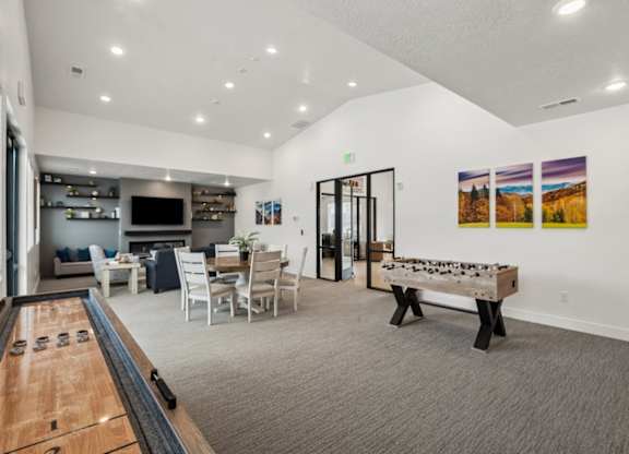 A billiard table is in the middle of a room with a couch, chairs, and pictures on the wall.