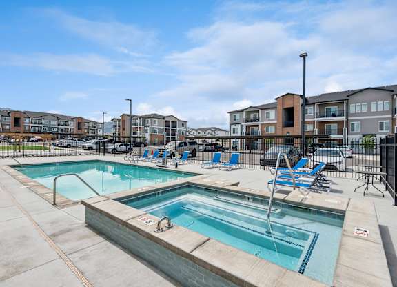 A swimming pool with a slide and chairs around it.