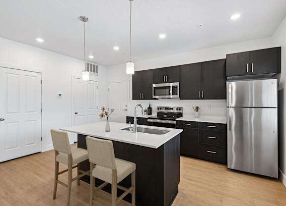 A modern kitchen with a center island and stainless steel appliances.