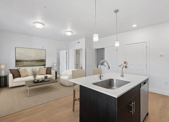 A modern kitchen with a white countertop and a large painting on the wall.