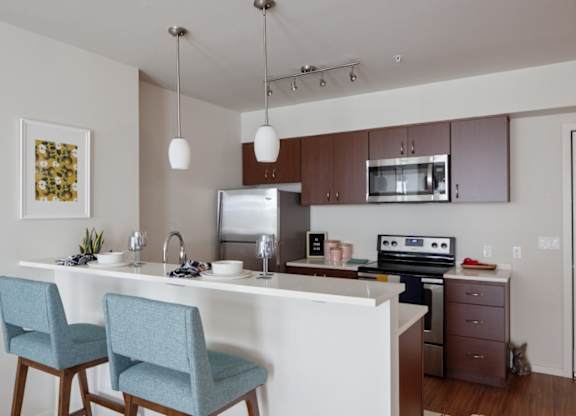 A kitchen with a white countertop and blue chairs.