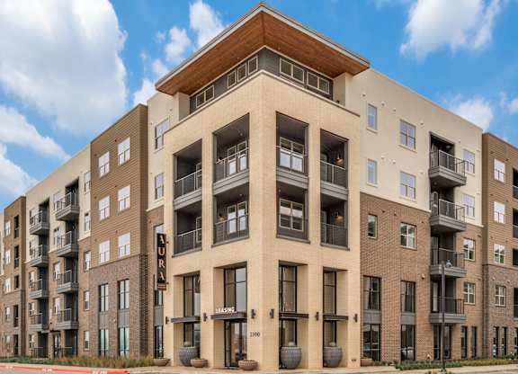 A large apartment building with a brown and beige exterior.