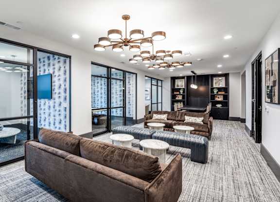 A modern living room with a brown sofa and a chandelier.