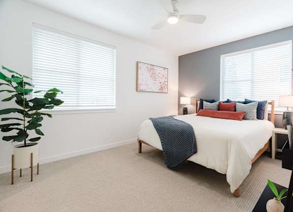 A bedroom with a bed, pillows, and a ceiling fan.