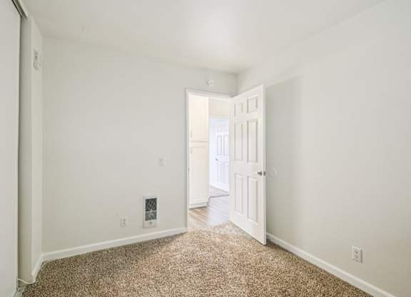 A room with a carpeted floor and a doorway leading to another room.