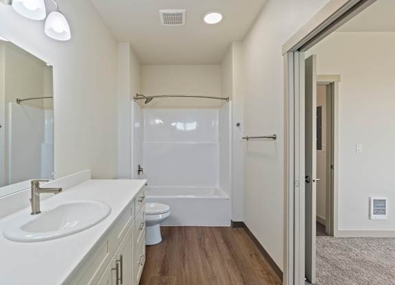 A white bathroom with a sink, toilet, and shower.