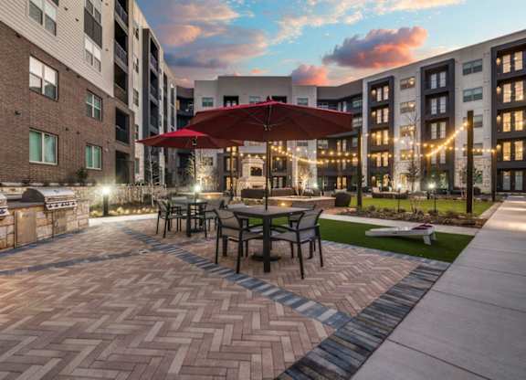 A patio with a table and chairs under a red umbrella.