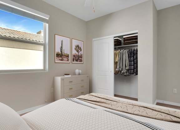 A bedroom with a large bed, a dresser, and a window with a view of a roof.