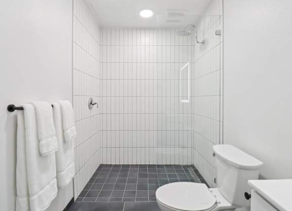 A white toilet sits next to a white sink in a white tiled bathroom.