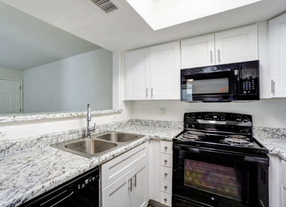 A kitchen with a black oven and white cabinets.