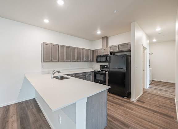 A modern kitchen with a white countertop and black appliances.