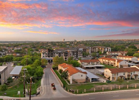 A sunset view of a residential area with houses and a road.
