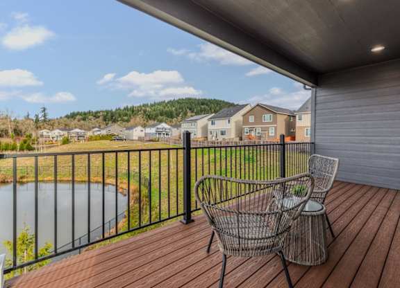 A deck with two chairs and a table overlooking a lake.