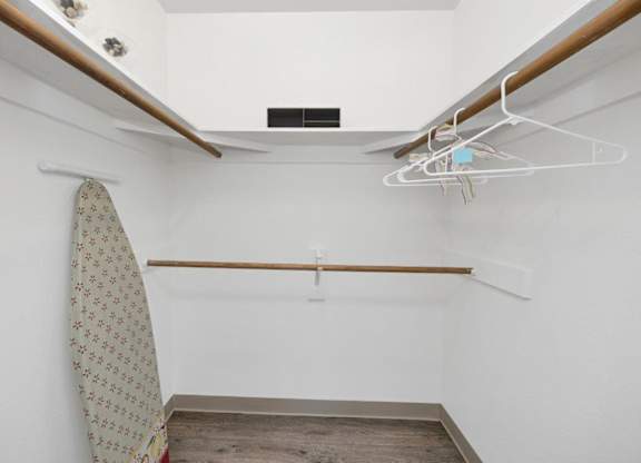 A white closet with a tie hanging on a rod.
