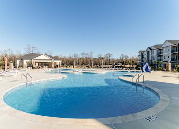 A large outdoor swimming pool with a slide and a building in the background.
