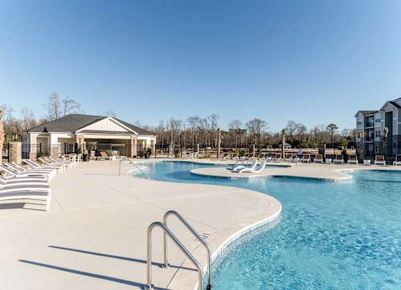 A large outdoor swimming pool with a diving board and a building in the background.