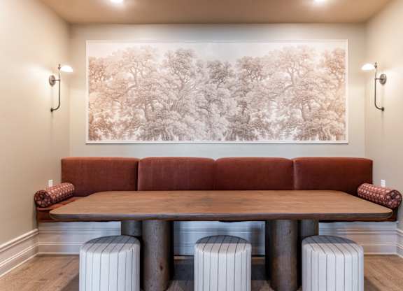 A living room with a brown couch and a large picture of trees on the wall.