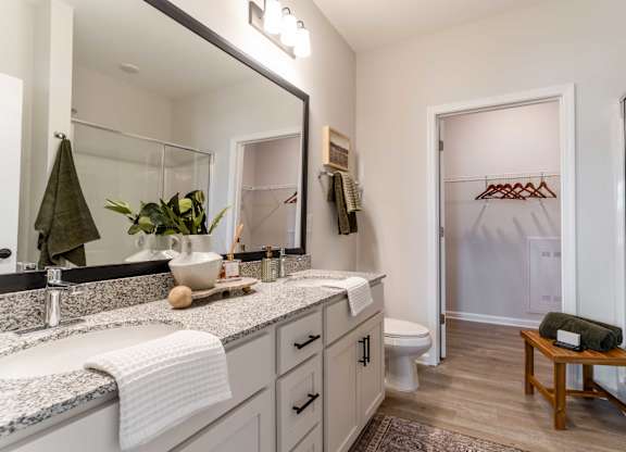 A bathroom with a large mirror, a sink, a toilet, and a wooden stool.