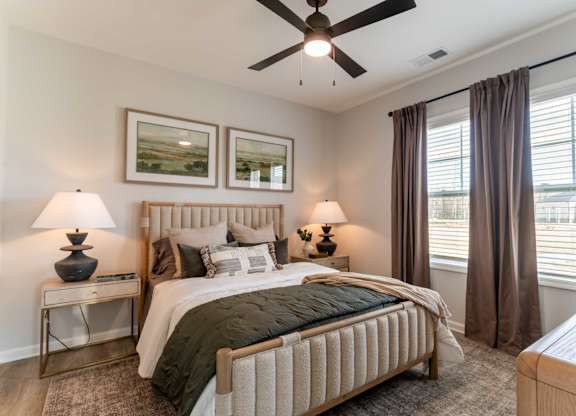 A bedroom with a large bed, two lamps, and a ceiling fan.