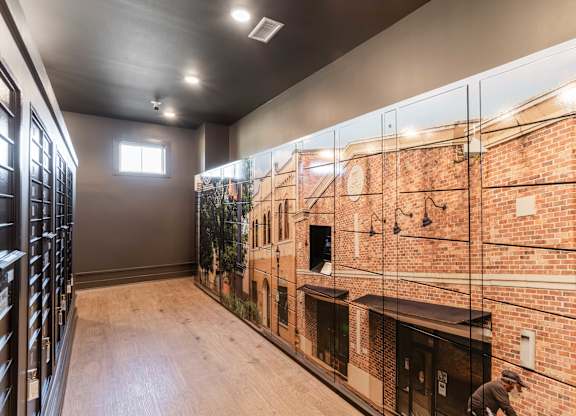 A man is working on a brick wall in a room with wooden floors and a glass wall.