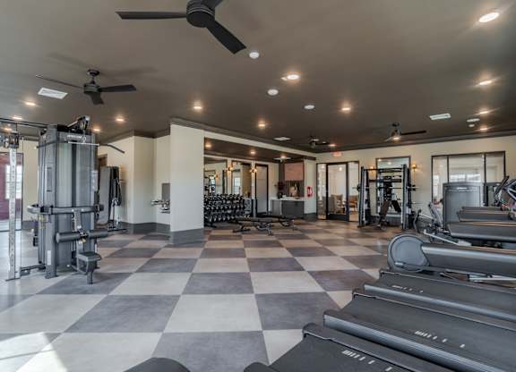 A spacious gym with a variety of equipment and a checkered floor.