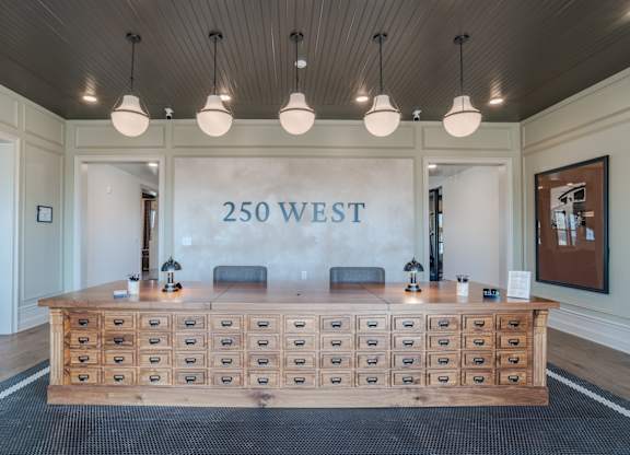 A reception area with a long wooden desk and drawers in front of a sign that says 250 WEST.