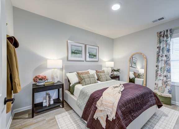 A bedroom with a bed, nightstand, and a mirror.