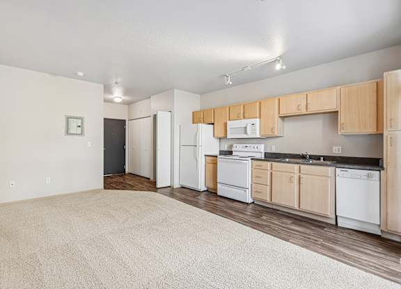 A kitchen with white appliances and wooden cabinets.