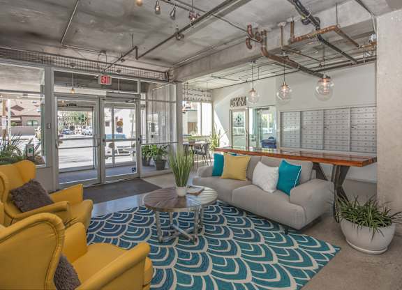 A brightly lit waiting area with yellow chairs and a blue patterned rug at Herbert Residential, Arizona 85701