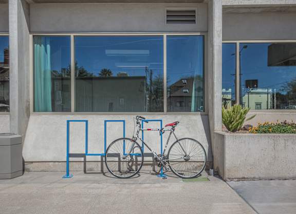 A bicycle is parked next to a blue bike rack at Herbert Residential, Tucson