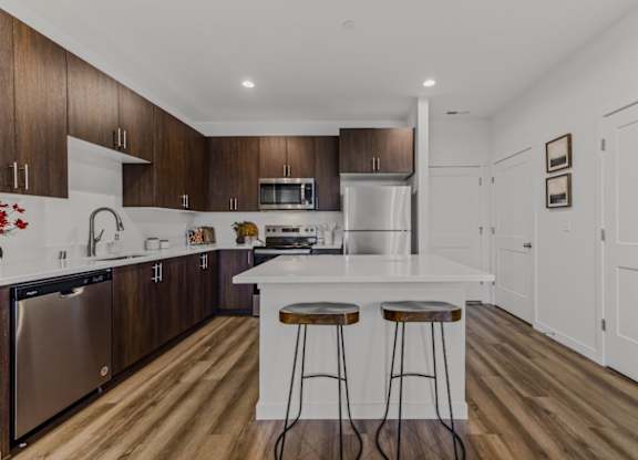 A kitchen with a white countertop and wooden cabinets.