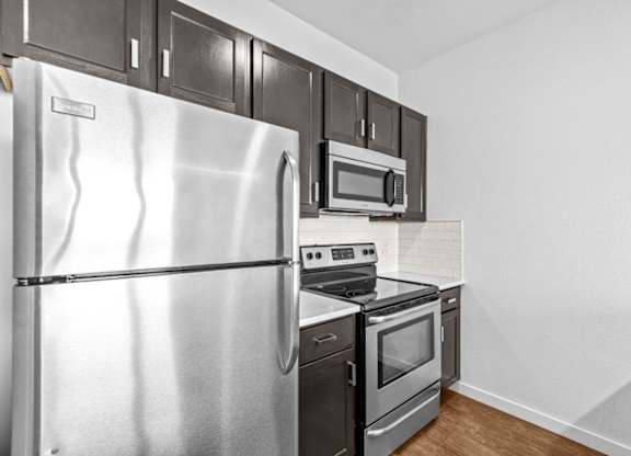 A kitchen with a stainless steel refrigerator, microwave, and oven.