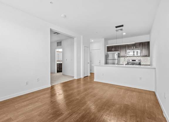 A spacious room with wooden flooring and white walls.