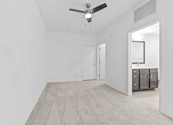 A spacious room with a ceiling fan and a carpeted floor.