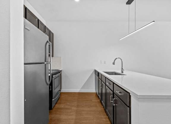 A kitchen with a refrigerator, sink, and cabinets.