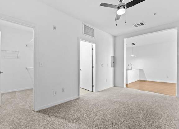 A room with a ceiling fan and carpeted floor.