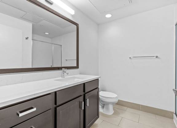 A white toilet sits in a bathroom with a sink and mirror.