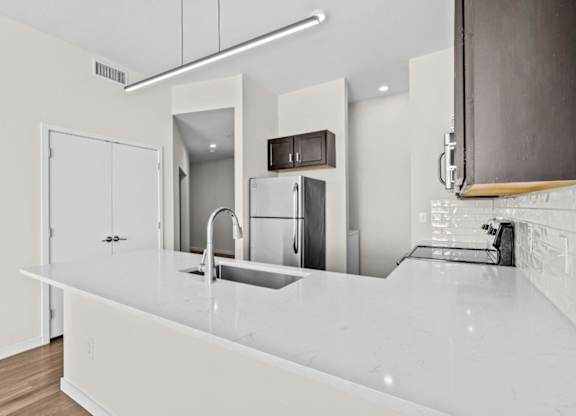 A modern kitchen with a white countertop and a sink.