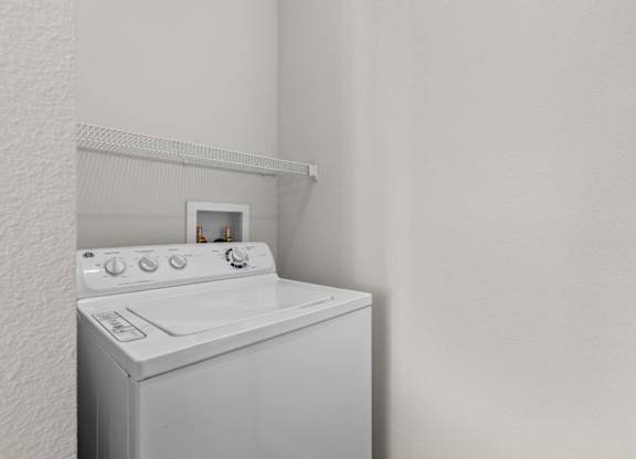A white washing machine in a white room.