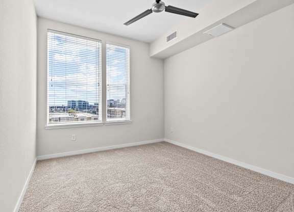 A room with a fan and a window overlooking a cityscape.