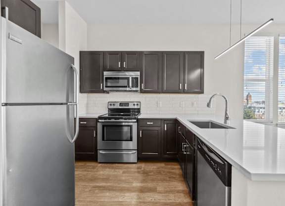 A modern kitchen with a refrigerator, oven, and microwave.