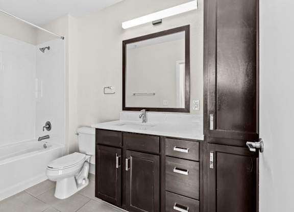 A white toilet sits in a bathroom next to a sink and a bathtub.