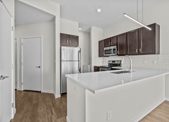 A kitchen with white countertops and brown cabinets.
