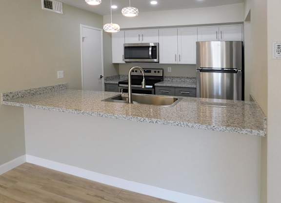A kitchen with a granite countertop and stainless steel appliances.
